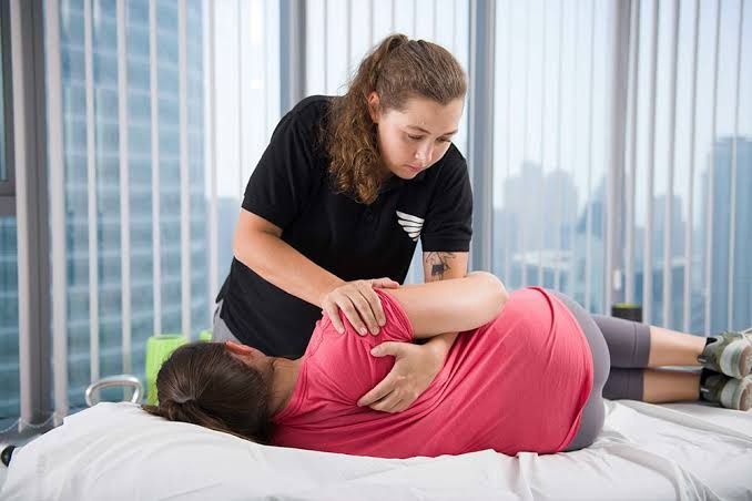 Home physiotherapy for frozen shoulder in Gurgaon with therapist assisting shoulder mobility exercises
